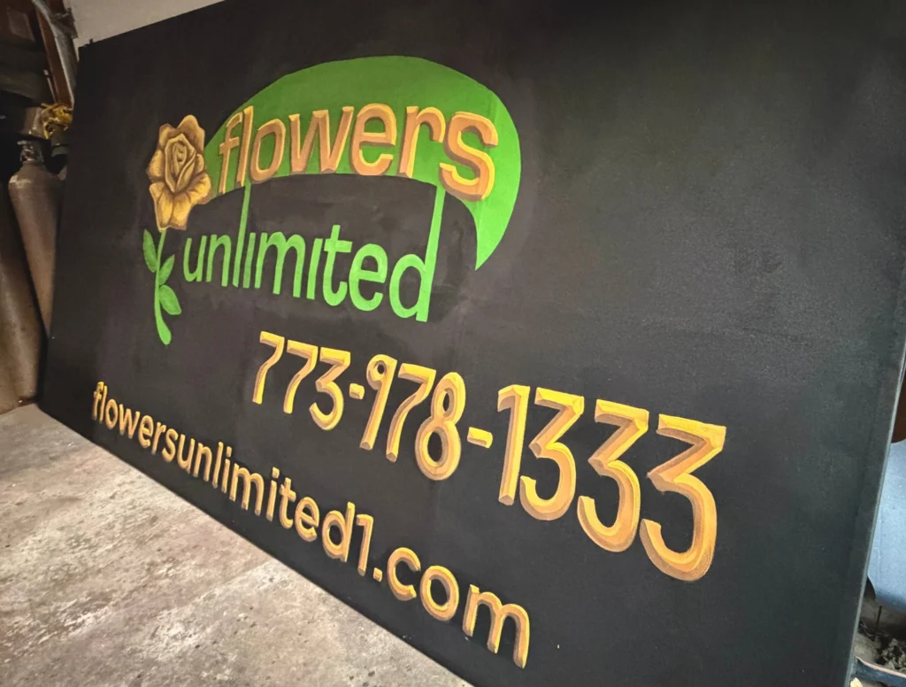 Flowers Unlimited Sign, hand-painted sign by Caleb Wassell: gold and green lettering with a golden rose, the phone number and website on a black board.