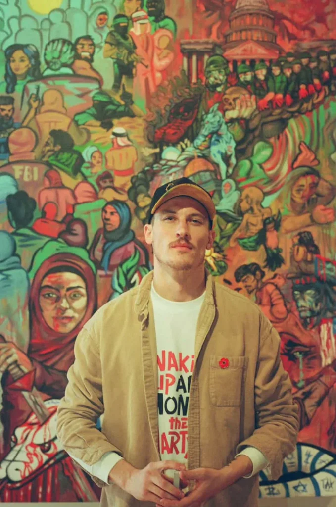 Artist Caleb Wassell standing in front of one of his large paintings
